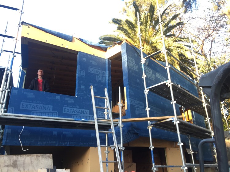 Front of house with wrap almost complete and Gavin standing in window frame. 